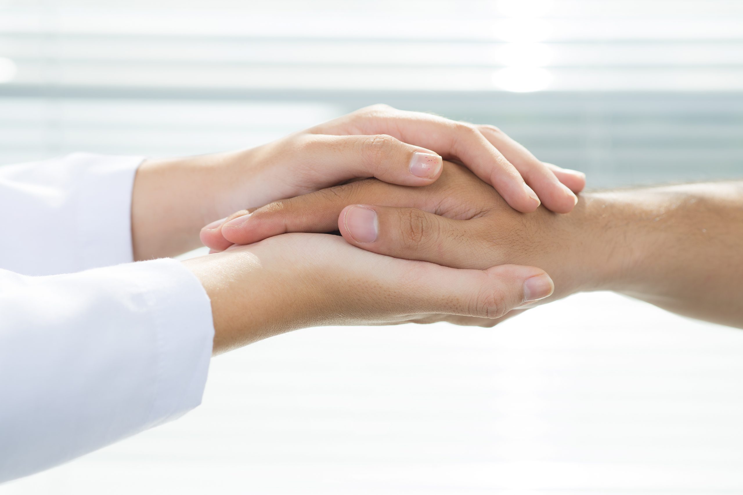 Two people holding hands for comfort